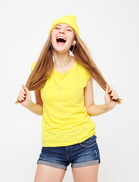 Chica en camiseta amarilla bailando con expresión de la cara inspirada.