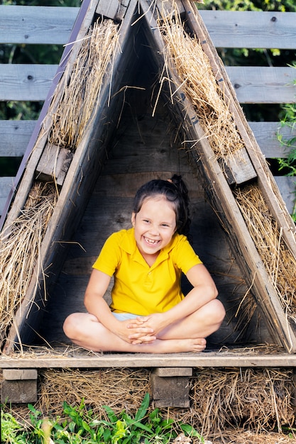 Chica con una camiseta amarilla brillante se sienta en una pequeña cabaña