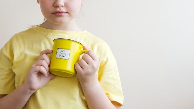 Foto chica con una camiseta amarilla con una taza amarilla en la mano