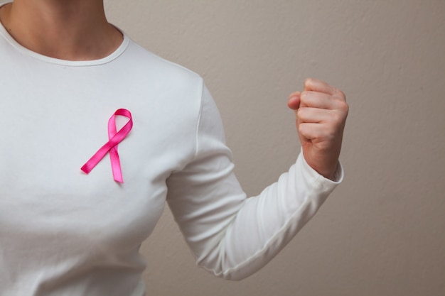 Foto chica con una camiseta blanca con una cinta rosa en su pecho derrotando al cáncer. mes de la conciencia del cáncer de mama. concepto de cáncer de mama