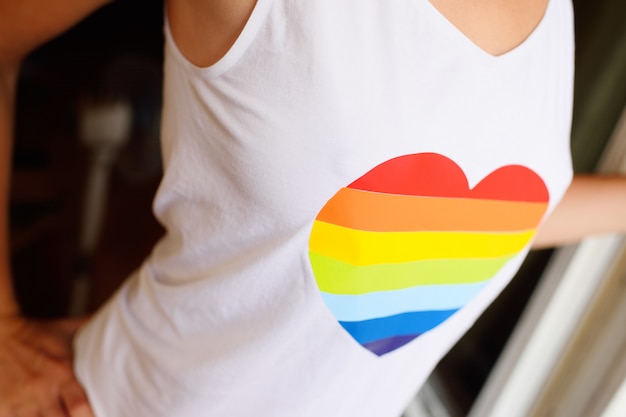 Una chica con una camiseta blanca con la imagen de un corazón con un arco iris. El concepto de LGBT