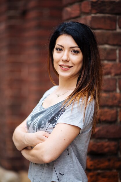 Chica en una camiseta gris sonriendo en la ciudad