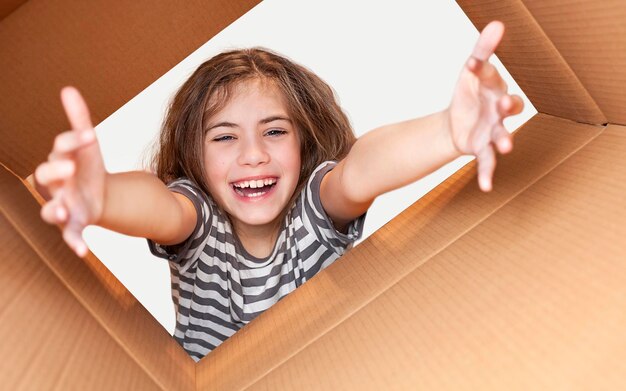 una chica con una camiseta a rayas mira dentro de una caja de cartón. concepto de entrega