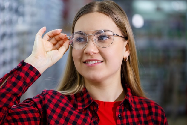 La chica de la camiseta saca y se mide las gafas.