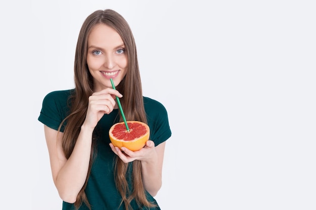 Chica en camiseta verde bebe pomelo