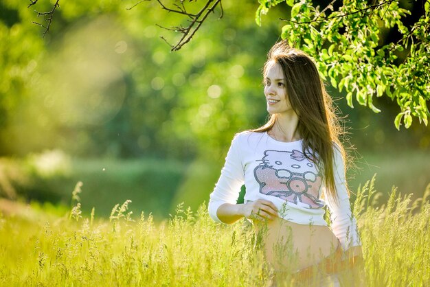 una chica en un campo con una camisa que dice hola gatito en él