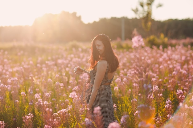 Chica en el campo floreciente de flores de Sally. Flores lilas y mujer