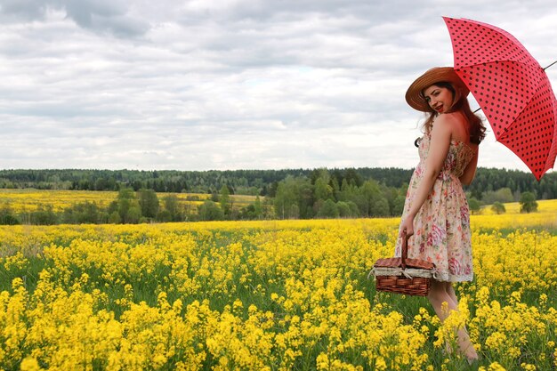 Chica en un campo de flores con un paraguas y un sombrero