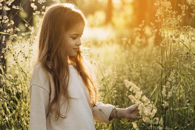 Foto una chica en un campo de flores con el sol detrás de ella