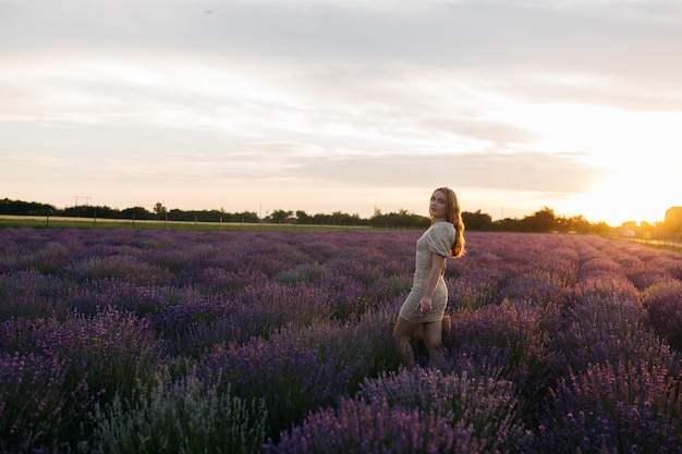 Chica en un campo de lavanda Mujer en un campo de flores de lavanda al atardecer con un vestido blanco Francia Provenza