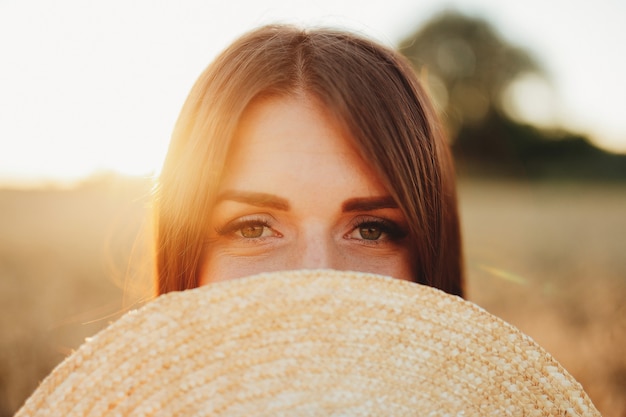 Foto chica en campo de trigo, mano de la chica y espiguilla de trigo, puesta de sol en el campo. foto de alta calidad