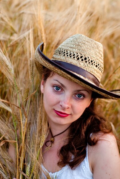 Chica en campo de trigo con vestido blanco y sombrero stetson. Enfoque selectivo.