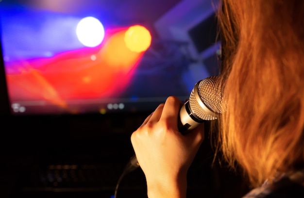 Chica canta karaoke en casa. Tiempo de cuarentena. Entretenimiento de autoaislamiento. Mujer sosteniendo el micrófono en las manos. Divirtiéndome solo.