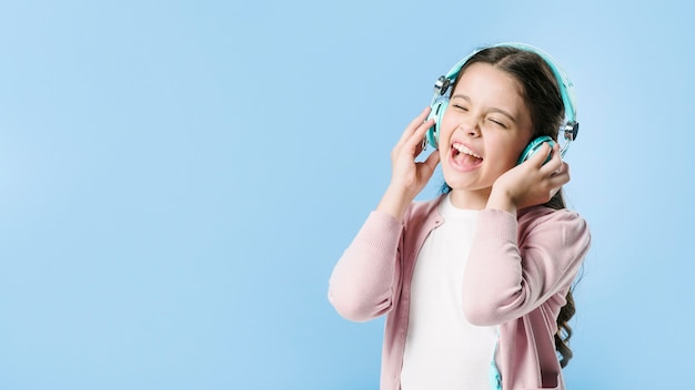 Foto chica cantando en auriculares en estudio