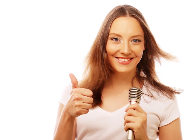 Chica cantando feliz Mujer de belleza con camiseta blanca con micrófono sobre fondo blanco