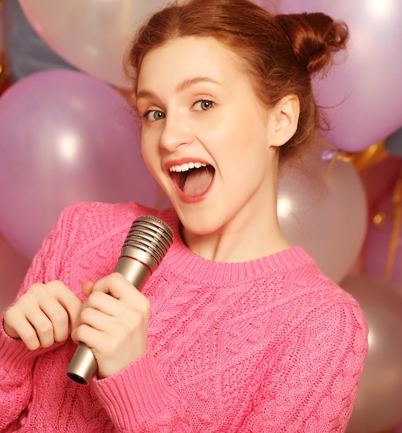 Chica cantando feliz Mujer de belleza con micrófono sobre fondo