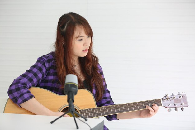 Chica cantando en el micrófono y tocando la guitarra