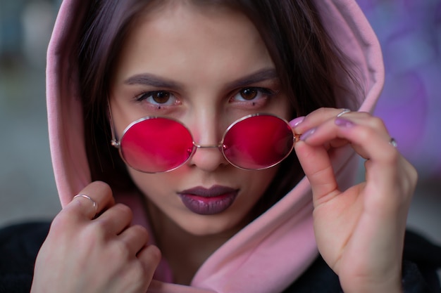 Chica en una capucha rosa ajusta gafas