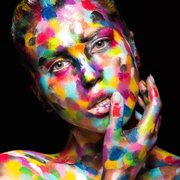 Chica con la cara coloreada pintada. Imagen de belleza de arte.