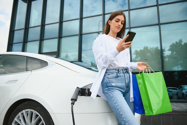 Foto chica cargando auto eléctrico en la gasolinera eléctrica