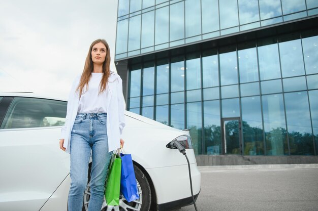 Chica cargando auto eléctrico en la gasolinera eléctrica