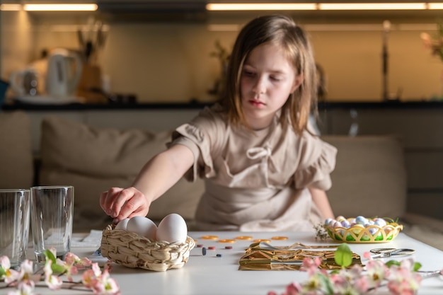 Chica en casa en la cocina tiñe huevos para Pascua