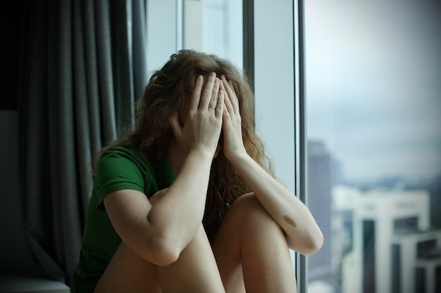 Foto chica en casa mira la ventana en depresión triste sentimiento de ansiedad y soledad pensamientos de