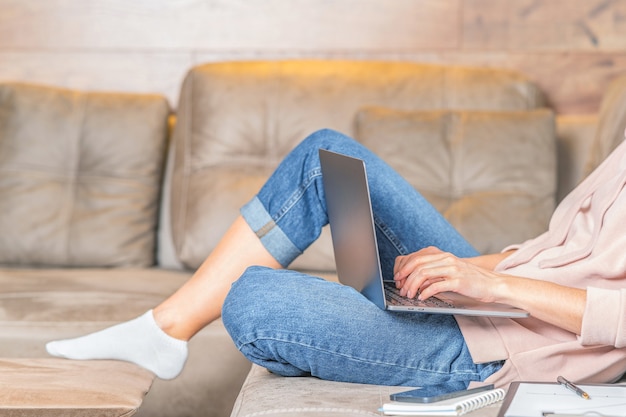 Chica en casa sentada en el sofá con laptop y navegar en línea.