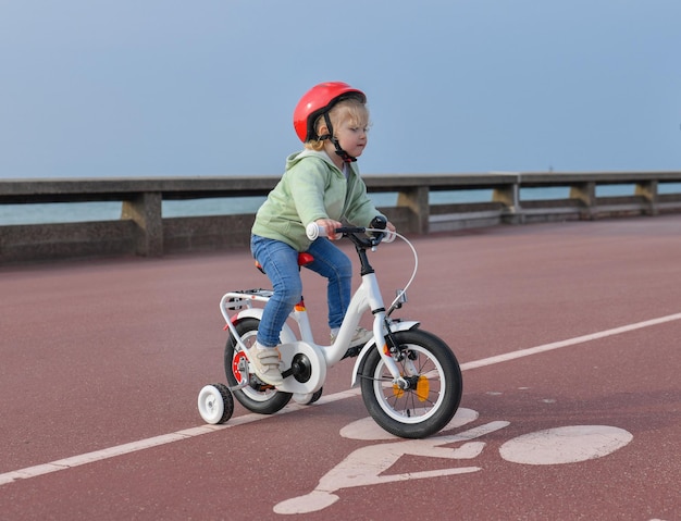 Chica en casco aprende a andar en bicicleta de cuatro ruedas