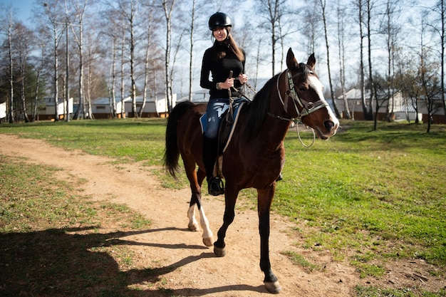 Chica con casco a caballo en el bosque