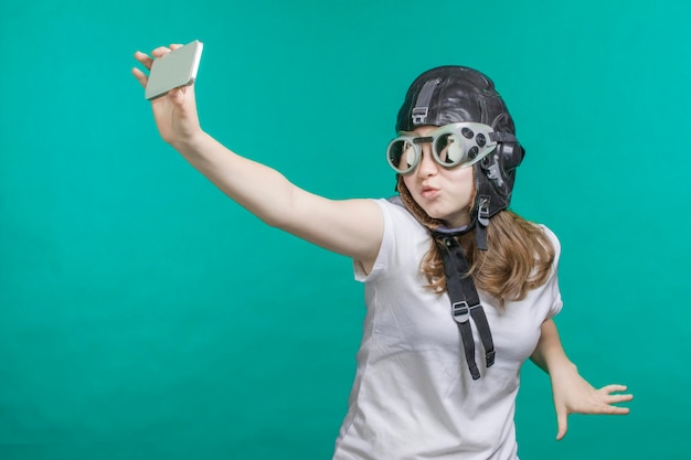 Chica con casco de piloto tomando una selfie por teléfono inteligente