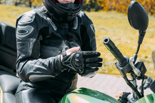 Una chica con casco protector de motocicleta se pone guantes