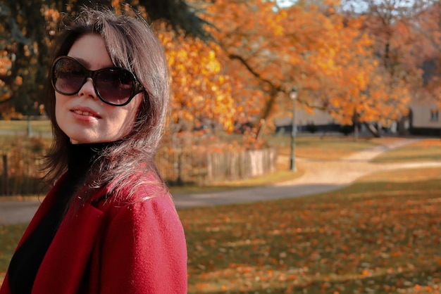 Chica caucásica con abrigo rojo y gafas de sol.