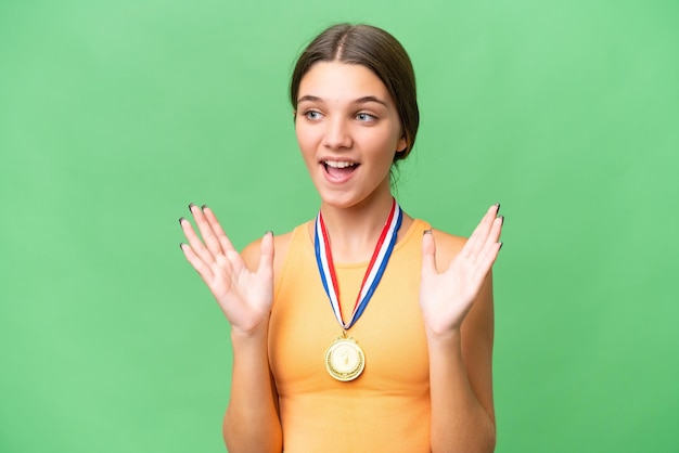 Chica caucásica adolescente con medallas sobre fondo aislado con expresión facial sorpresa