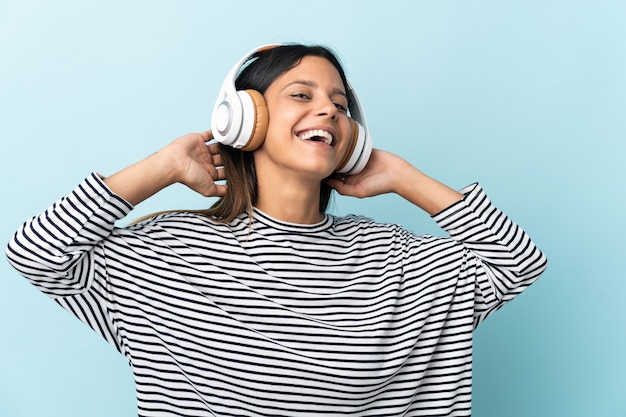 Chica caucásica aislada en azul escuchando música