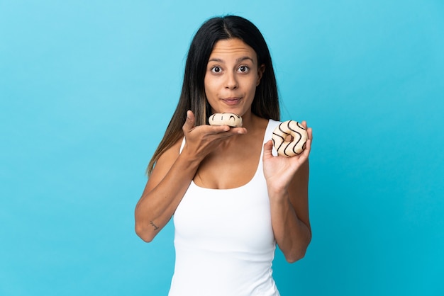 Chica caucásica aislada en la pared azul sosteniendo una rosquilla