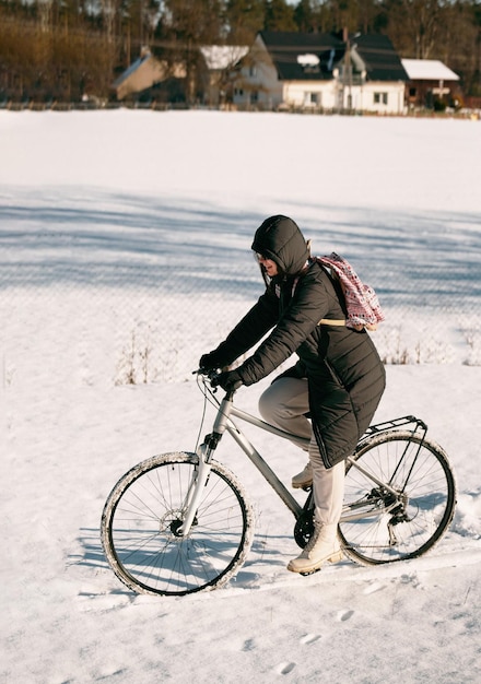 Chica caucásica ciclismo en carretera de nieve con una bicicleta Bicicleta de invierno deporte divertido ciclista feliz Mujer feliz andar en bicicleta en el bosque