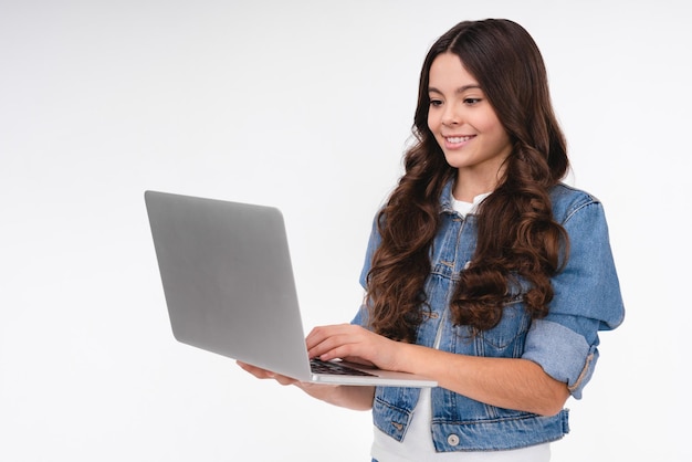 Una chica caucásica feliz usando una computadora portátil con ropa casual aislada en un fondo blanco