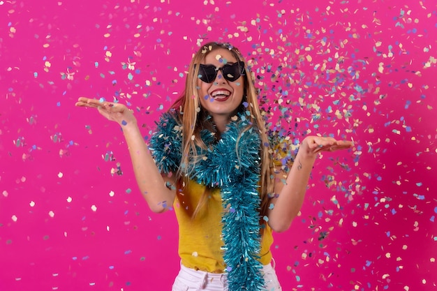 Chica caucásica de fiesta en la discoteca riendo tirando confeti aislado en un fondo rosa