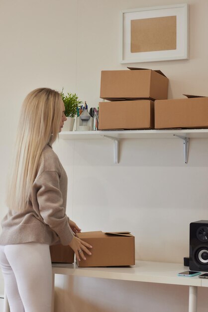 Chica caucásica grabando cajas para mudarse a un nuevo apartamento