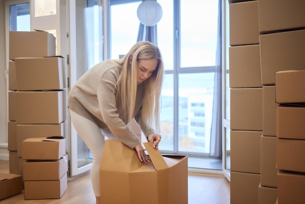 Chica caucásica grabando cajas para mudarse a un nuevo apartamento