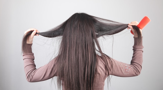 Chica caucásica mostrando su cabello con un peine en la mano.