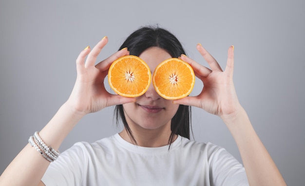 Chica caucásica sosteniendo cortar naranja.