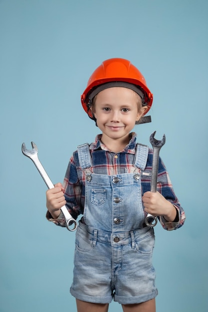 Chica caucásica en un traje de constructor sostiene una llave