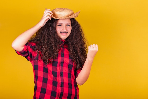 Chica caucásica vestida como un niño festa junina ropa mano en sombrero duda celebrando festivales espaciales negativos en mayo junio y julio