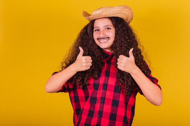 Chica caucásica vestida como un niño ropa de fiesta pulgar arriba festivales de aprobación afirmativa en mayo, junio y julio