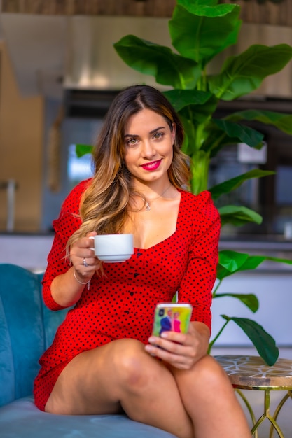 Chica caucásica en un vestido rojo tomando un café