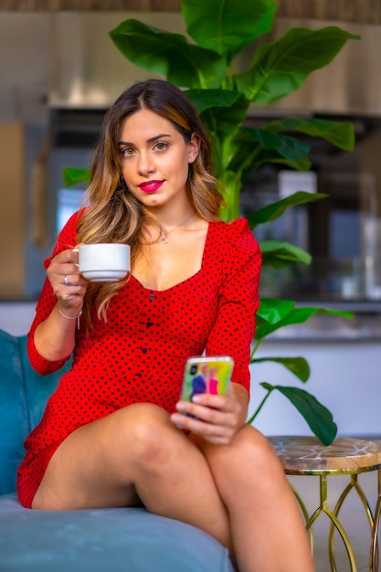 Chica caucásica en un vestido rojo tomando un café