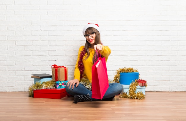 Chica celebrando las fiestas navideñas sorprendida mientras sostiene muchas bolsas de compras