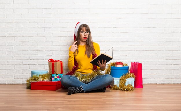 Foto chica celebrando las fiestas navideñas sosteniendo un libro y sorprendida mientras disfruta de la lectura